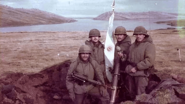 Cuatro soldados argentinos en una trinchera en Puerto Yapeyú sosteniendo un mortero y un rifle FAL